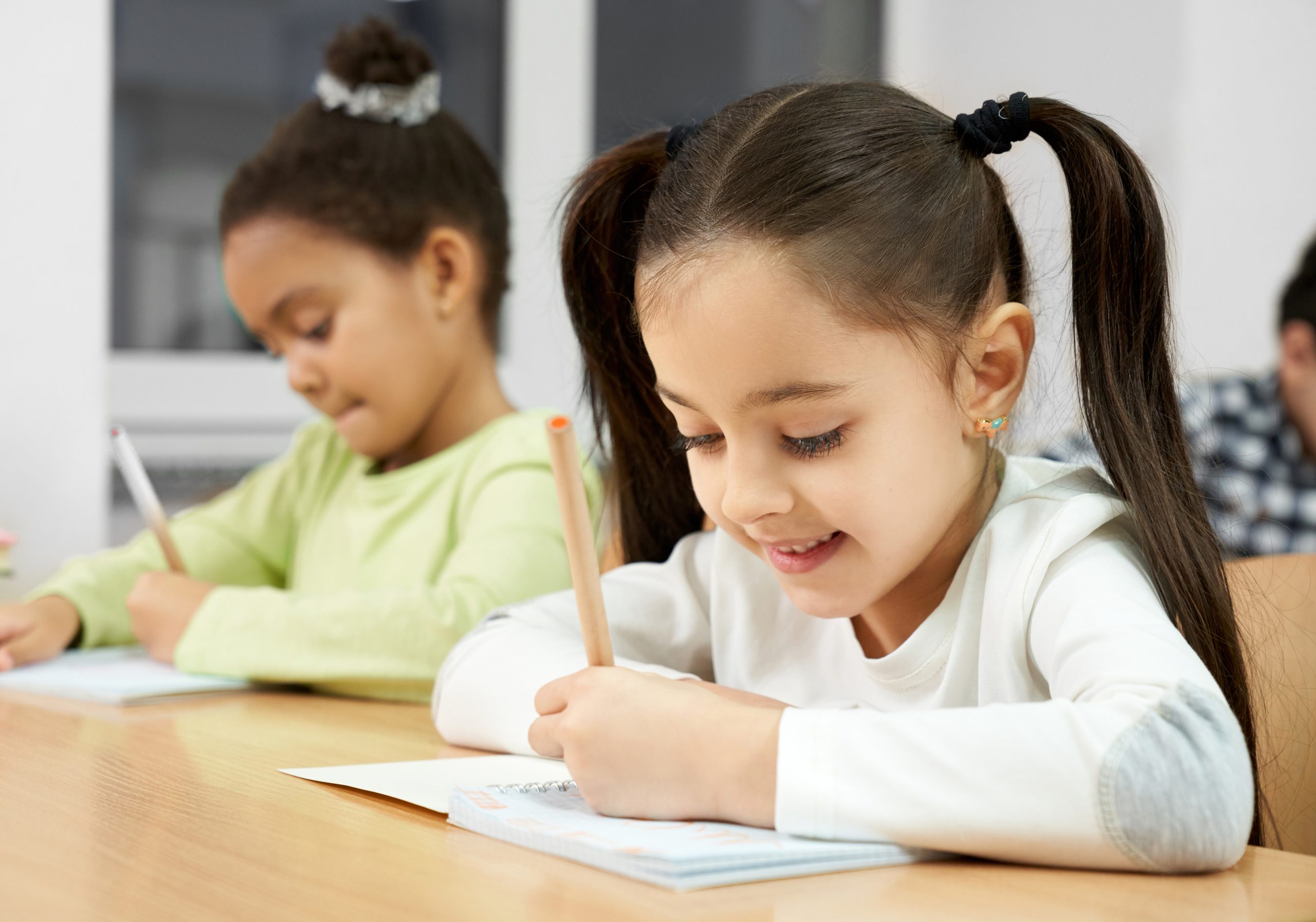 Happy student sitting at table and writing in copybook